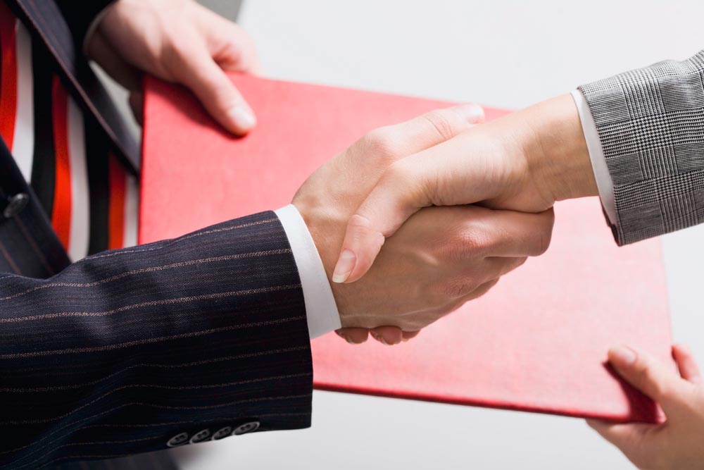 Moment of making an successful agreement: handshake and exchange of documents